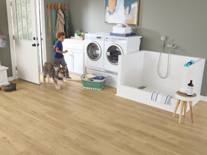 Boy and dog running through laundry room with Pergo flooring