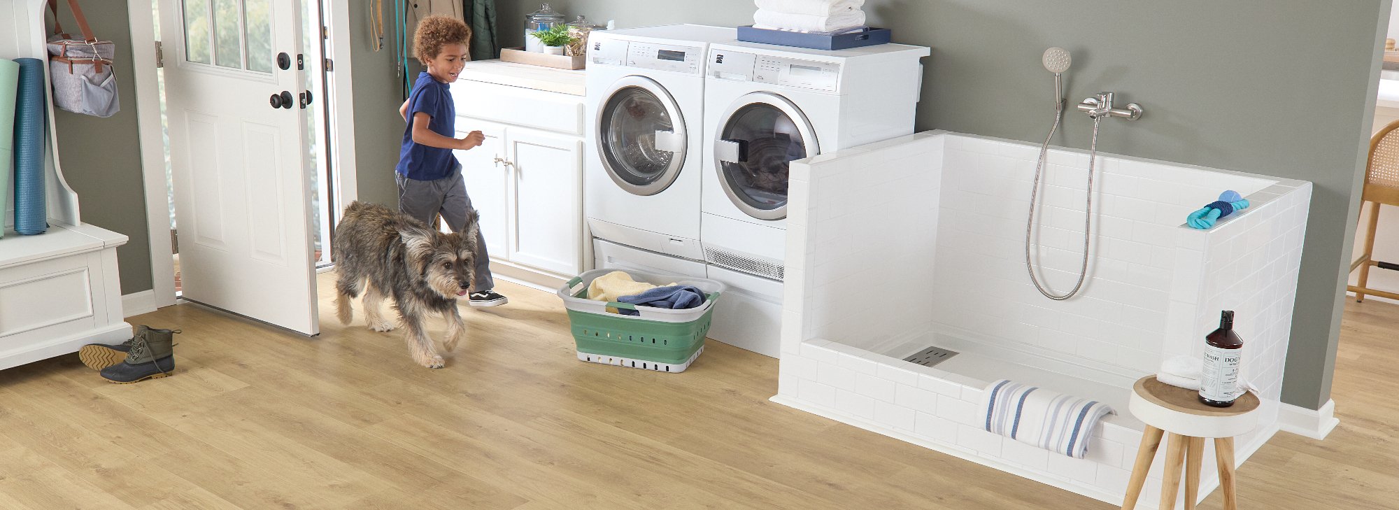 Boy and dog running through laundry room with Pergo flooring